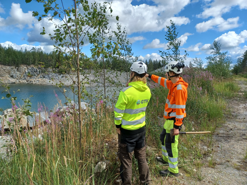 Kaksi geologia kenttätyössä kirkkaissa vaatteissa