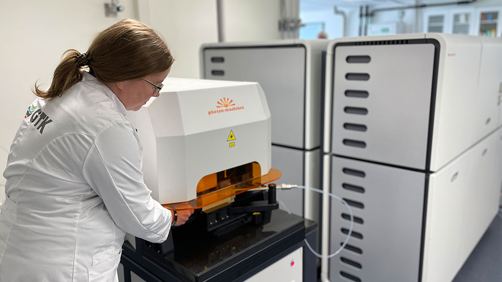Iso laboratoriolaite, johon laboratoriohenkilö on laittamassa näytettä sisään.