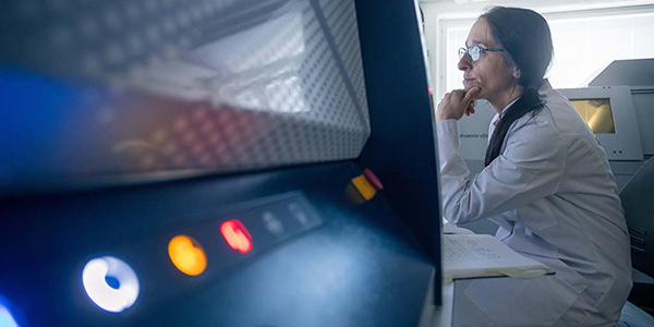 Henkilö tarkastelee laboratoriolaitteen mittaustuloksia tietokoneen näytöltä.