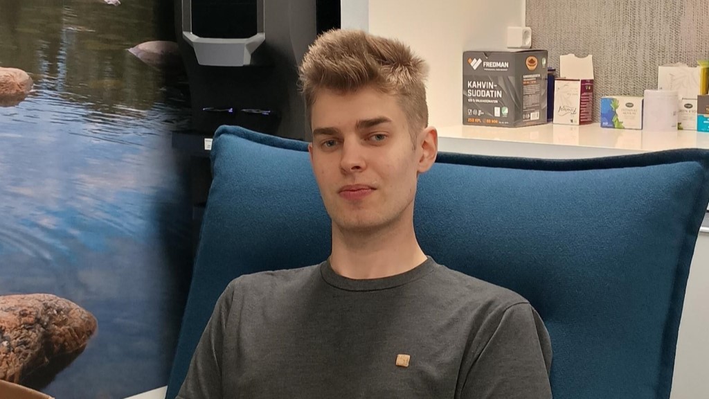 Henkilö istuu sinisessä nojatuolissa toimistossa.
