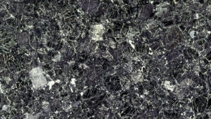 Tummanvärinen kivipinta, jossa on vaaleita suonia ja laikkuja.