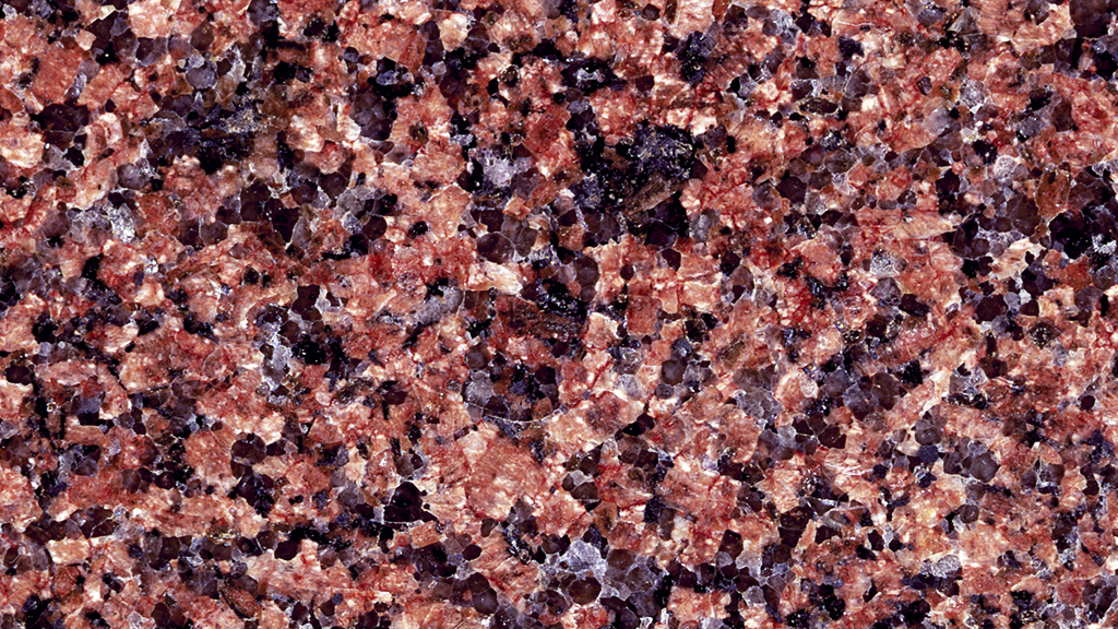 Kivipinta, jossa on punaisia, mustia ja harmaita rakeita.