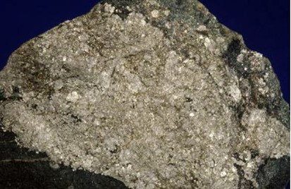 Kivinäyte, jossa on vaalea, kiteinen keskiosa ja tummempi reuna.