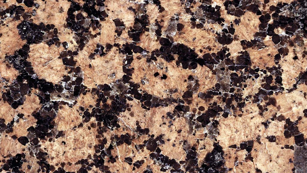 Kuvassa on kivi, jossa on ruskea pohja ja tummia, kulmikkaita kiteitä.