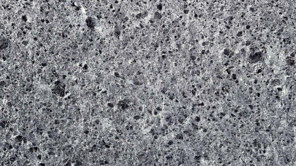 Kuvassa on harmaa kivi, jossa on pieniä, tummia reikiä ja huokosia.