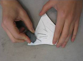 Kädet raaputtavat mustalla kivellä valkoista posliinikappaletta.