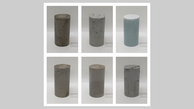 Six cylindrical concrete samples in a row, each with a ruler beside it.