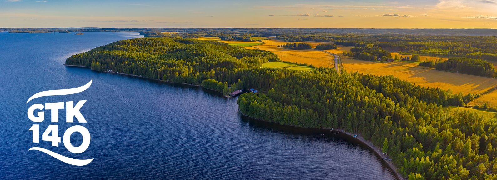 Järvi, metsää, peltoja ja tie ylhäältä kuvattuna.