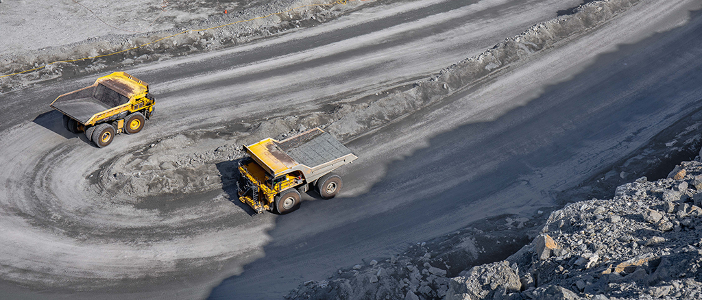 Kaksi kaivoskippiautoa ajamassa kaivosalueen tietä avolouhoksessa.