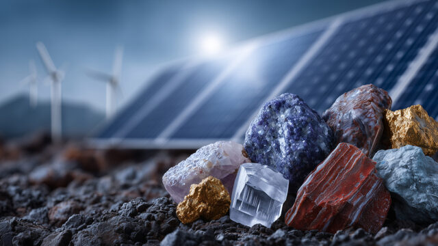 Rocks on ground with solar panels and wind turbines in background
