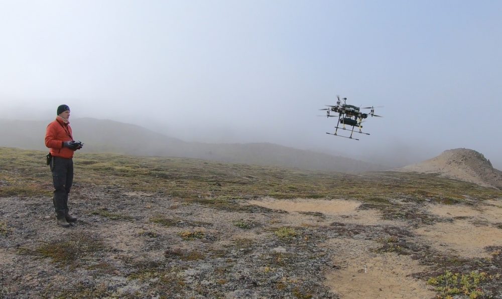 Figure 1. HZDR-HIF’s multi-copter Tholeg THO-R-8/10 equipped with a Sensys MagDrone R1 magnetometer. Robert Zimmerman (HZDR-HIF) is controlling the landing during field operations in Greenland in 2019 (Photo: Heikki Salmirinne, GTK).