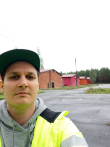 Mies seisoo punaisten rakennusten edessä