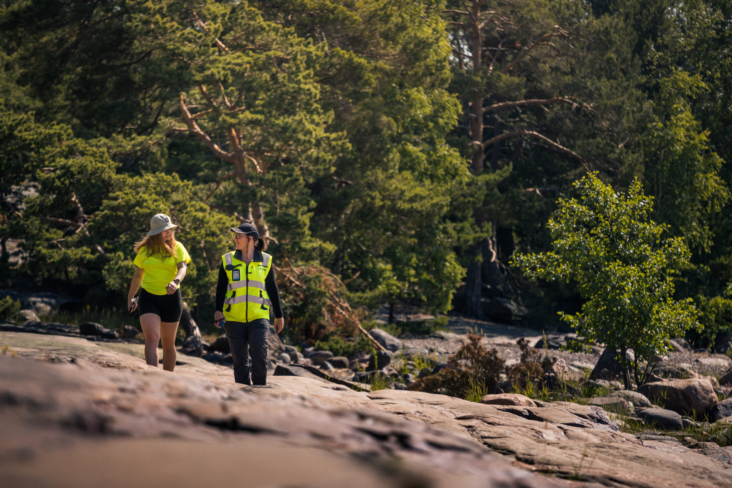 Two people walking on the rocks with safety vests talking to each other