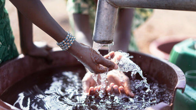 African girl transporting water from a well in a natural environment.